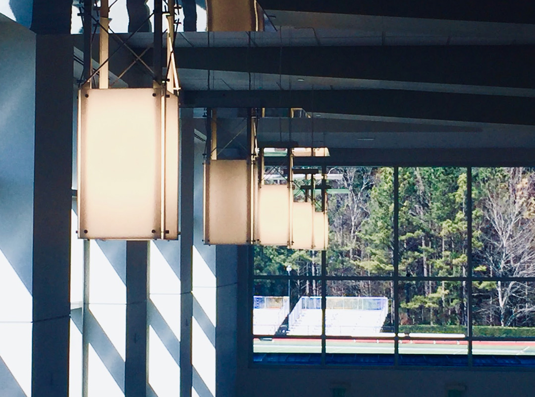 Artistic student photo of hanging lights in the Middle School campus looking out onto the football field